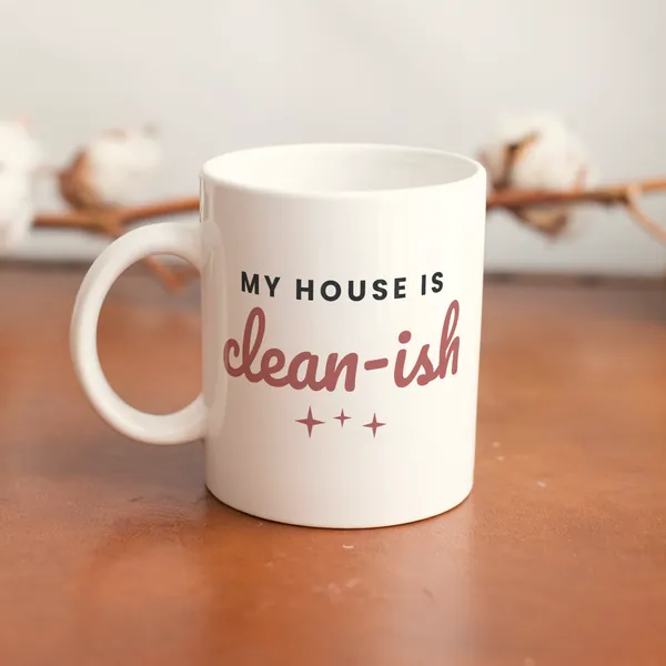 White 11 oz ceramic mug printed with "My House Is Clean-ish" on a wooden table