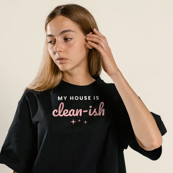 Model wearing a black "My House Is Clean-ish" tee with the light-ink version of the design