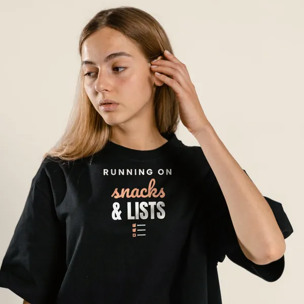 Model wearing a black "Running on Snacks and Lists" tee with the light-ink version of the design